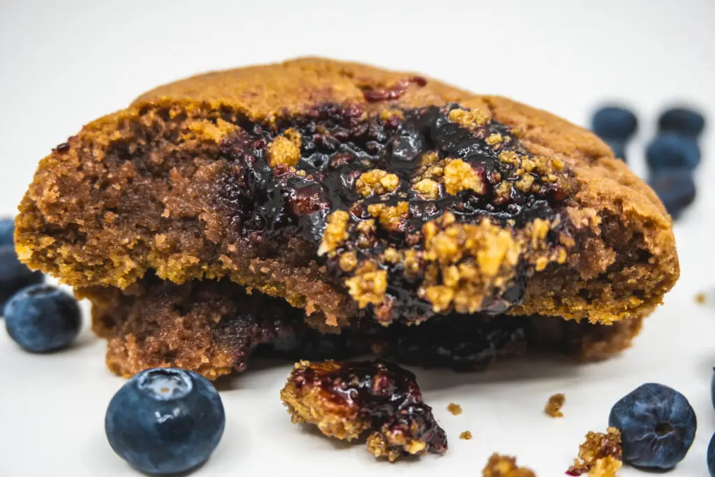 Berry Graham cookie broken open, blueberry filling and graham crumble inside, fresh blueberries alongside